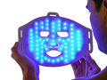Man holding LED blue light therapy face mask for acne treatment and skin care
