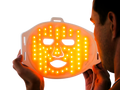 Man holding LED orange light therapy face mask for skin treatment and rejuvenation