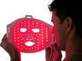 Man holding LED red light therapy face mask for skin rejuvenation and acne treatment