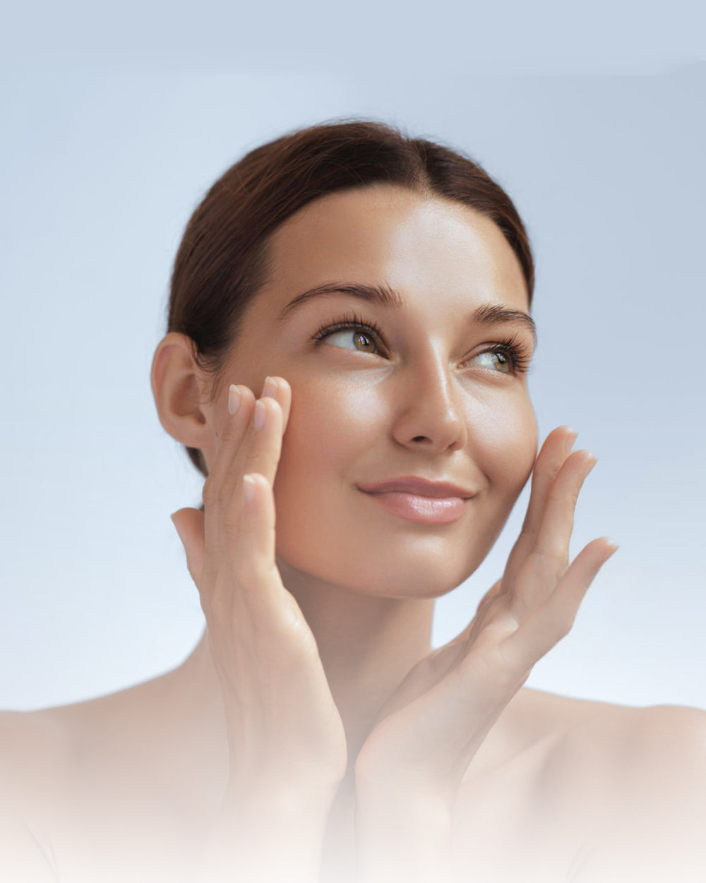 Woman with glowing, healthy skin gently touching her face, showcasing skincare results